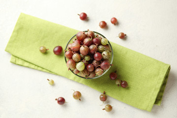 Red and green gooseberries, ripe berries on table in plate.