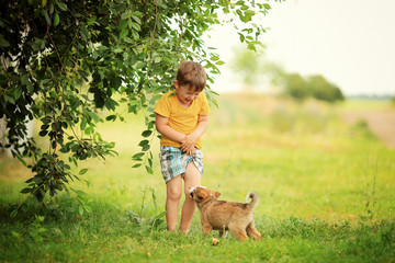 cheerful boy in a yellow t-shirt with a puppy