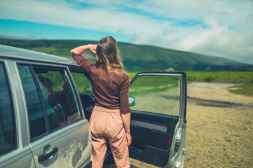 Young woman relaxing by her car on the moor in summer