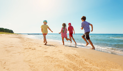 Fototapeta na wymiar Happy kids on vacations at seaside running in the water