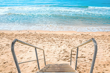 view of steps with a handrail leaders on the clean sandy beach
