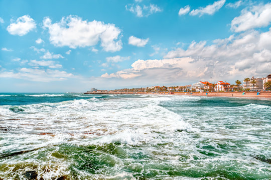 View on the town and the beach from sea with big waves, Sitges, Spain