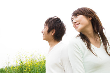 Obraz premium 菜の花の前で背中合わせに立つカップル