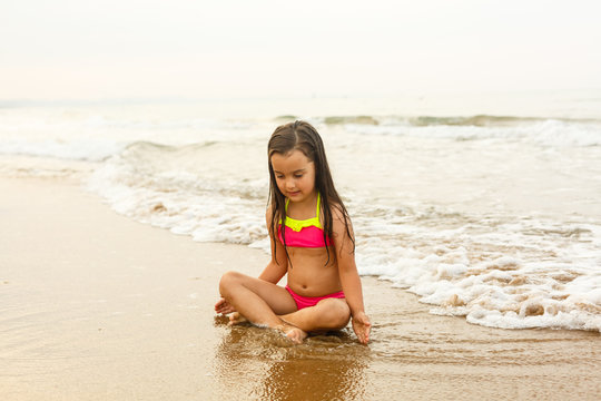 Happy girl on a tropical beach ocean has a fun with splash