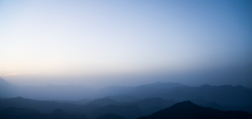 landscape with silhouettes of blue mountains with mist and cold sunlight