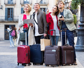 Two couples with luggage search for sights on map