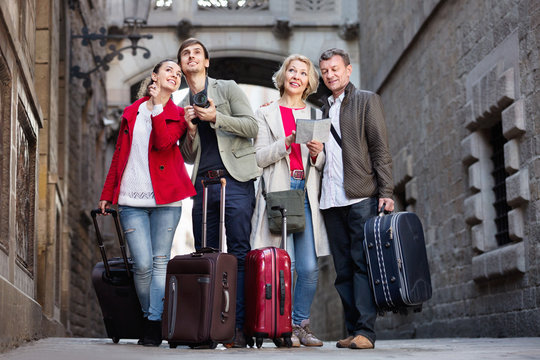 Two couples with luggage search for sights on map