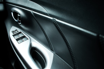 Naklejka premium Car interior details of the door handle with control panel, window adjustment.