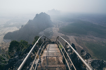 Mountain peak with empty stairs going down during sunrise foggy morning in Hpa-An, Myanmar