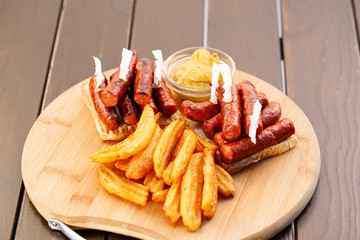 Spicy sausages on toast bread with fried potato on wooden plate , wood background.