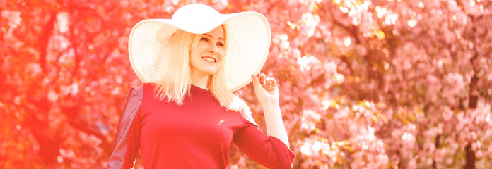 Beautiful spring girl in fragrant pink flowers in summer blossom park. Woman in a blooming garden . Fashion, Cosmetics & Perfumes . Curly blonde hair