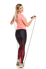 Young sporty woman posing with jumping rope on white background