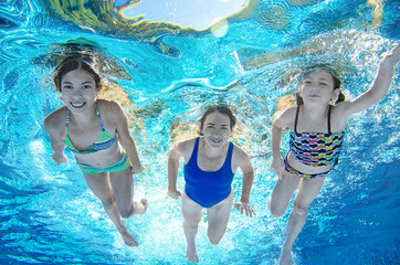 Obraz na płótnie Canvas Family swims in pool underwater, happy active mother and children have fun under water, fitness and sport with kids on summer vacation on resort