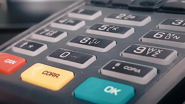 Macro closeup review of the pos terminal and pin pad numbers. Red yellow and green button. Keyboard on black POS terminal.