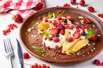 Homemade pancakes with sour cream and berries on a white background, horizontal photo