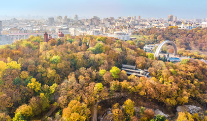 Aerial drone view of autumn pedestrian Park bridge, yellow fall trees, Truhaniv island, Dnieper river and Kyiv cityscape from above, city of Kiev, Ukraine