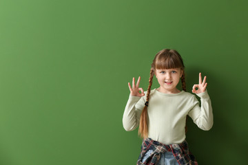 Cute deaf mute girl using sign language on color background