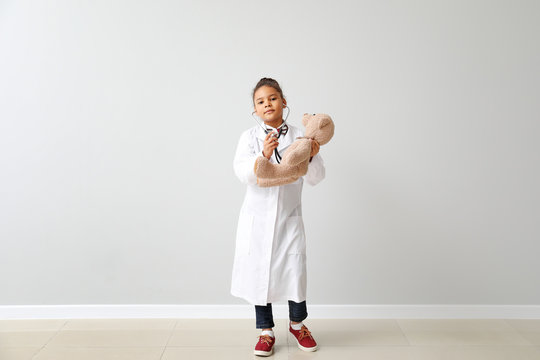 Little African-American doctor near white wall