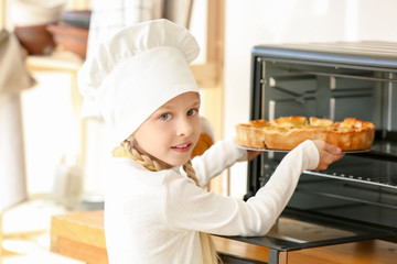 Cute little chef taking pie out of oven