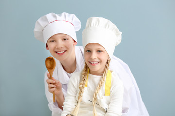 Cute little chefs on color background