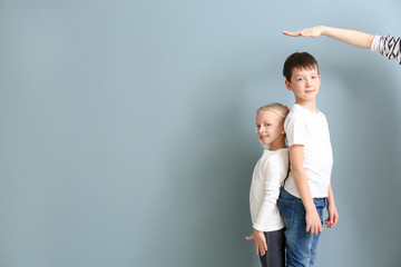 Mother measuring height of her children near wall