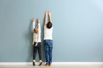 Cute little children measuring height near wall