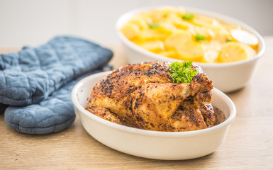 Whole chicken roasted in a porcelain bowl with potatoes