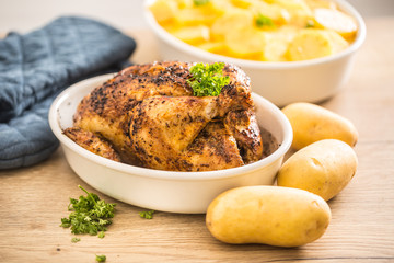 Whole chicken roasted in a porcelain bowl with potatoes