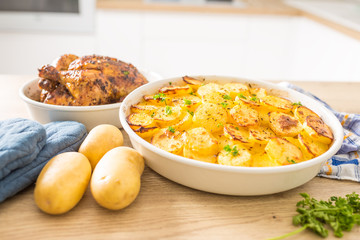 Traditional meal roasted potatoes and whole chicken on home kitchen table