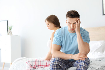 Upset young couple after quarrel sitting on bed