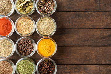 Collection of spices in bowls on wooden background with copyspace. Top view