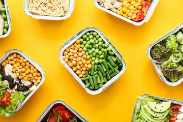 Many containers with delicious food on color background