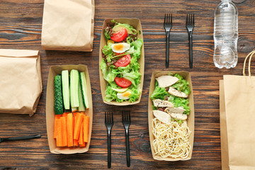 Containers with delicious food on wooden background
