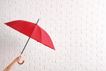 Female hand with stylish umbrella on white brick background