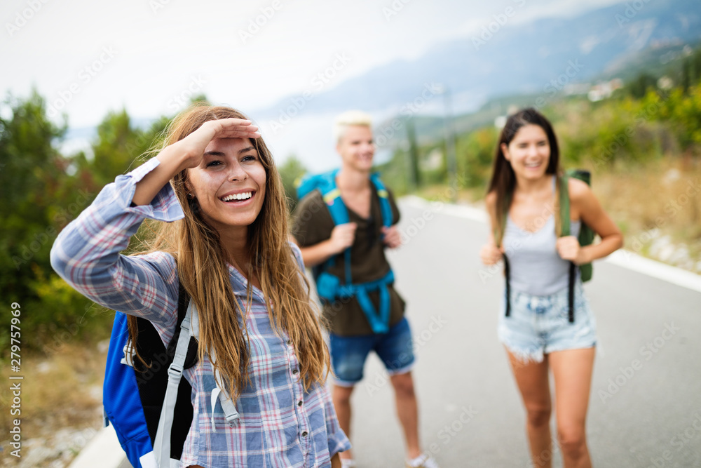 Wall mural group of young people with backpacks walking together by the road