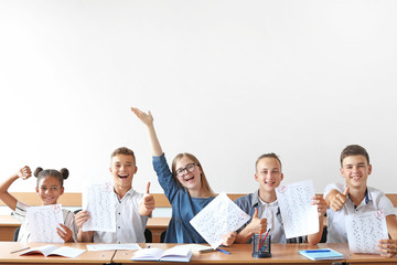 Happy classmates with results of school test in classroom - obrazy, fototapety, plakaty