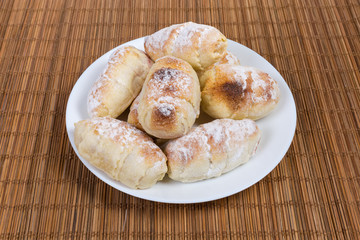 Baked sweet rolls with filling on dish on table mat