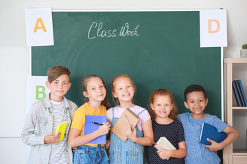 Cute little pupils near blackboard in classroom