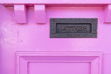 Letter box in a roughly painted rustic pink door