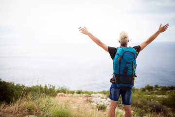 Fototapeta premium Happy man on mountain enjoying landscape. Travel, vacation, adventure, freedom concept