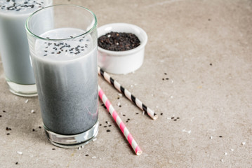 Trendy vegan food recipes, Black Sesame Iced Latte or smoothie with sesame seeds, dried coconut and Almond milk, grey stone table, copy space