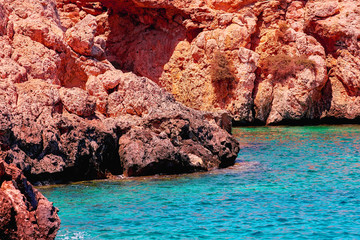 Glowing warm waves of Cyprus Larnaca with nice sun reflection stars, splashing and red rocks
