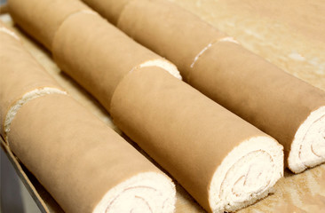 Biscuit rolls with filling and condensed milk are on the table. Sweet and roll for dessert. Confectionery production, cake