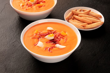 Salmorejo, Spanish cold tomato soup, on a black background with picos, typical breadsticks