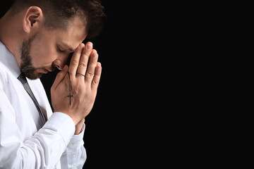 Religious man praying on dark background