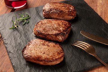 Sirloin beef steaks with rosemary and red wine on a black slate plate