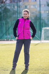 Young sporty woman standing on a football field. Female in sportswear exercising outdoors