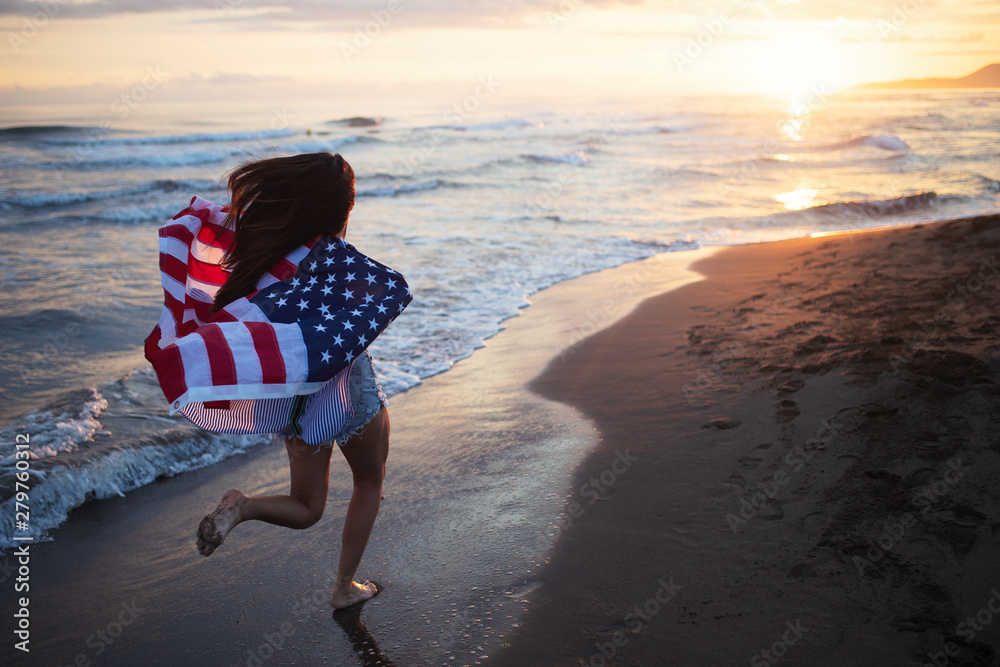 Wall mural happy woman running on beach while celebrateing independence day and enjoying freedom in usa