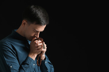 Religious man praying to God on dark background