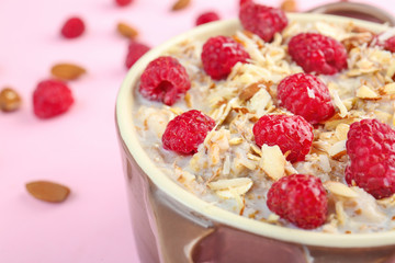 Pot with tasty sweet oatmeal on color background, closeup